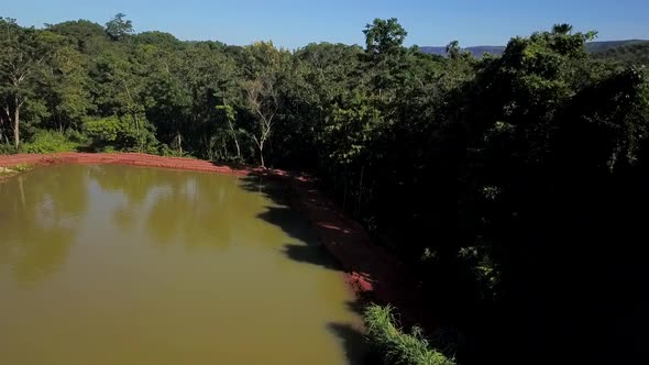 Drone flying backwards over a small pond on a fish farm in the Tocantins region of Brazil alt