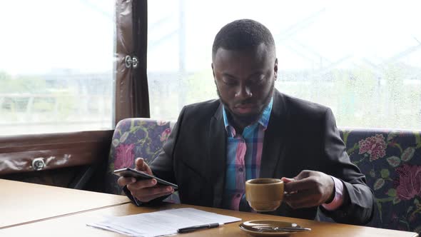 Afro American Businessman is Typing a Message on Smartphone alt