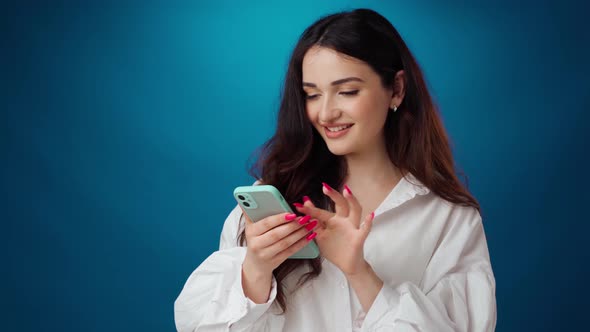 Young Woman Using Smartphone Against Blue Background