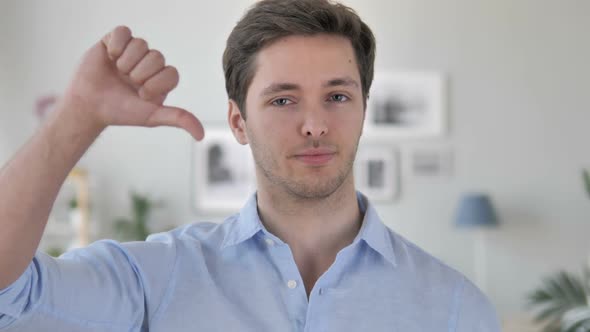 Thumbs Down By Handsome Young Man at Work Looking at Camera alt