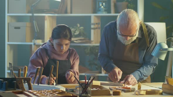 Grandfather Carpenter with His Teenage Granddaughter Works in the Workshop