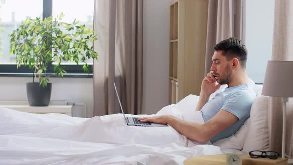 Man with Folder Calling on Phone in Bed at Home