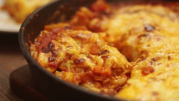 Unrecognizable cook cutting yummy gratin with veggies and tomato sauce alt