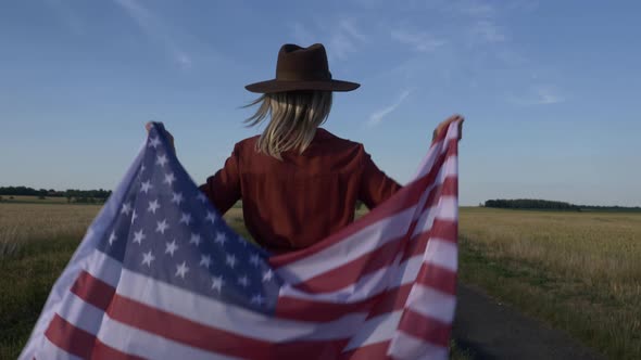 Woman in USA flag and hat on country road