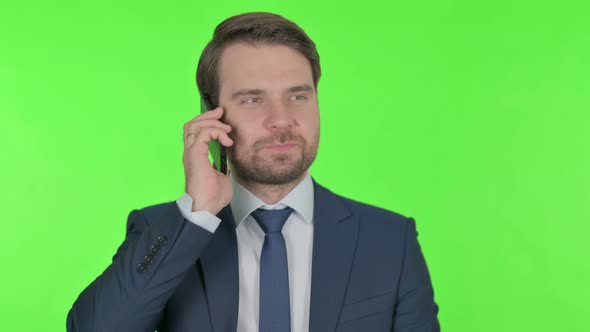 Young Businessman Talking on Phone on Green Background alt