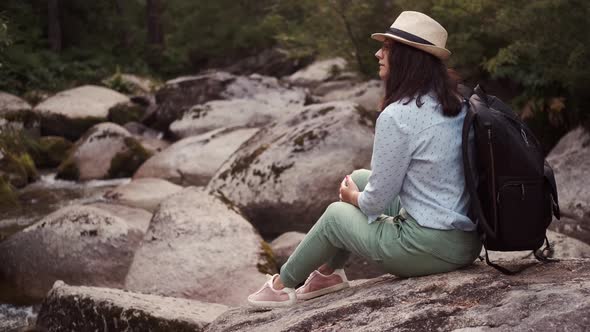 Portrait of a Traveler Resting Sitting on Stones By the River alt