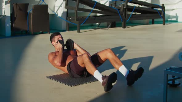 Handsome Athletic Man Practice Abs Exercises with Dumbbell on Open Cruise Ship Deck
