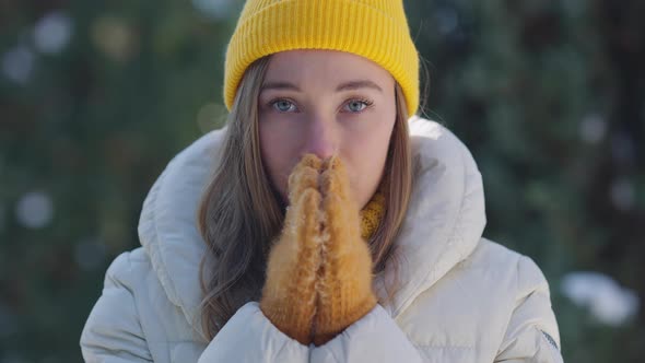 Portrait of Slim Beautiful Young Caucasian Woman in Yellow Hat and Mittens Rubbing Hands Looking at alt