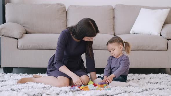 Beautiful Mother and Toddler Daughter Are Playing Construction Toys Together in a Room alt
