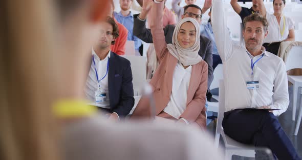 Audience at a business presentation raising their hands to ask questions alt