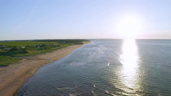 Sun setting over the Atlantic Ocean at Thunder Cove Beach in Prince Edward Island during summer time alt