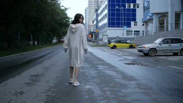 Video of a Female Student in a Beige Dress Walking Around the City on a Road