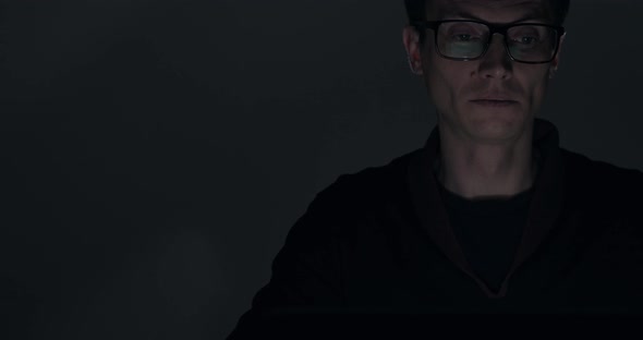 Portrait of a Man Working on Laptop Late at Night in Dark Room