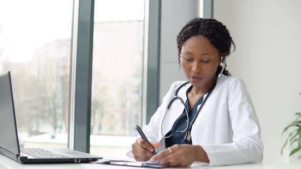 Young African American Woman Doctor Having Chat or Consultation on Laptop alt