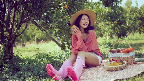 young asian attractive female wearing casual dress sit relax picnic in orange fresh garden alt