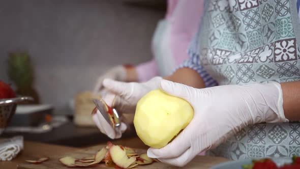 Woman in Gloves Peeling Apple