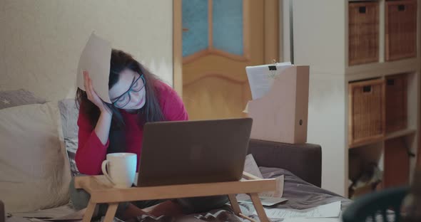A Young Woman Remotely Works at Home on Laptop in Bed During Coronavirus Quarantine alt