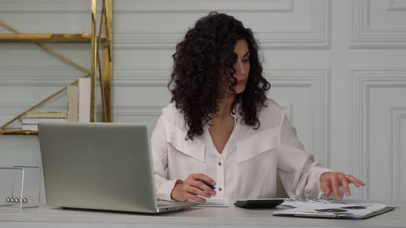 Indian Creative Curly Blackhaired Woman Covers Her Face with Her Hand and Gets Upset From Working in alt