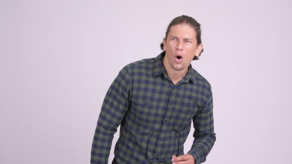 Handsome Hipster Man Looking Shocked and Removing Eyeglasses alt