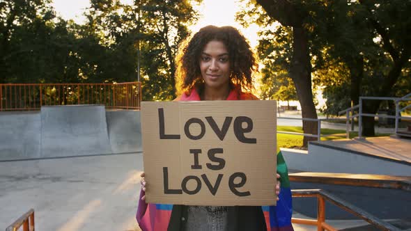 Darkskinned Woman Covering Multicolored LGBT Flag alt