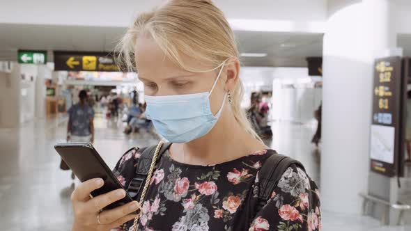 She Checking Messages Before the Flight. Woman in Mask with Cell at the Airport