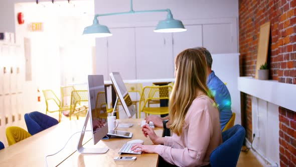 Business executives talking while working on computer alt