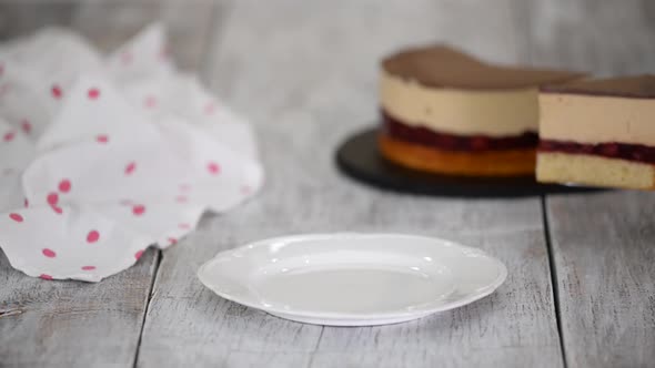 Woman Baker is Putting a Piece of Cherry Cake with Caramel Mousse on a White Plate
