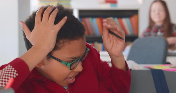 Angry School Bully Throwing Paper Ball at New African Boy Sitting at Desk in Classroom alt