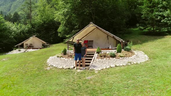 Aerial view of couple standing in front of sitting area at a camping site. alt