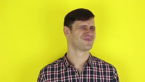 A Funny Handsome Guy Says No and Shakes His Head Negatively. Portrait on a Yellow Background.