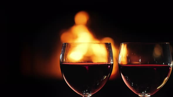 Two Glasses of Red Wine Against the Background of The Fireplace Where the Fire Burns alt