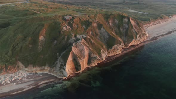 Beautiful Mountain Covered In Green Grass on the Shoreline of the Calm Ocean alt