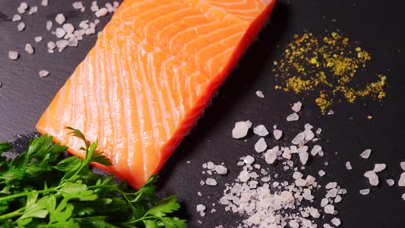 Delicious Fresh Salmon with Salt and Spices on a Black Stone Table