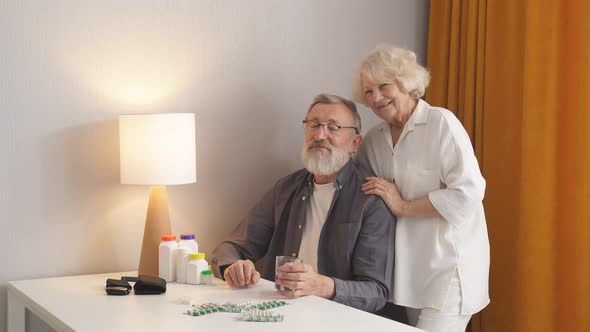 Senior Couple at Home Behind Table with Pills