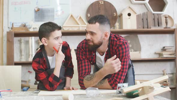 Father and Little Son Giving High Five While Visiting Woodworking Masterclass. alt