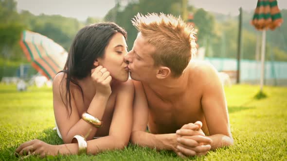 Beautiful Young Romantic Couple Lying Down on the Grass Having Fun at Water Park in Summer Day Dolly