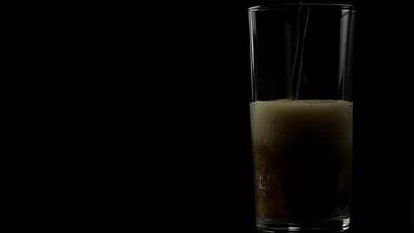 Cold Soda Drink Is Poured Into An Empty Glass On A Black Background