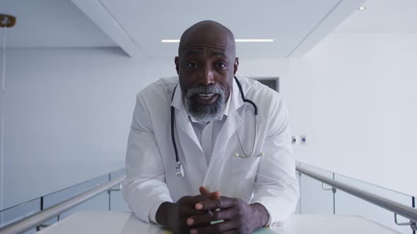 Portrait of african american male senior doctor talking looking at the camera at hospital alt
