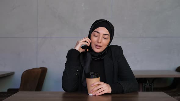 Young Muslim Woman in Hijab Talking on the Phone Whit Coffee