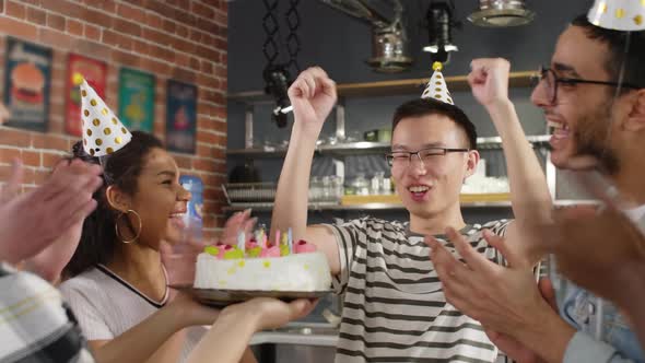 Asian birthday man puffing out cake candles