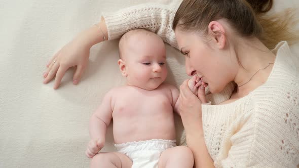 Loving Mother Stroking Hugging and Smiling at Her Little Baby Son Lying on Bed alt