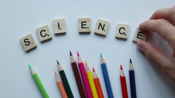 Hand Writing Word Science with Wooden Letters with Colorful Pencils on White Background alt