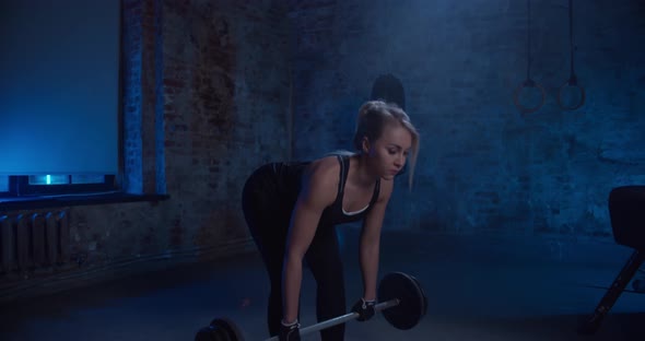 Fit Pretty Woman Performing the Deadlift Workout with Barbell in Gym
