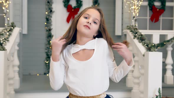 Portrait of a Baby Girl Smiling and Posing at the Camera Near the House on Christmas Night alt