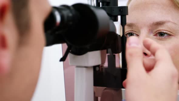 Optometrist examining female patient on slit lamp alt