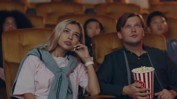 Attractive cheerful young caucasian woman watching horror movie in cinema theater.