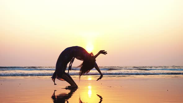 Silhouette of Young Woman Doing Gymnastic Bridge on the Beach