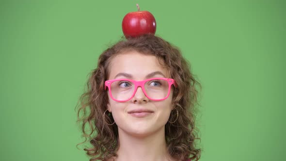 Young Happy Beautiful Nerd Woman with Red Apple on Top of Her Head alt