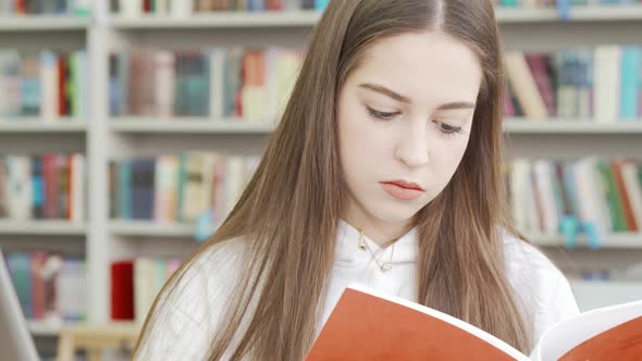 Teenage Girl Reading a Book at the Library alt