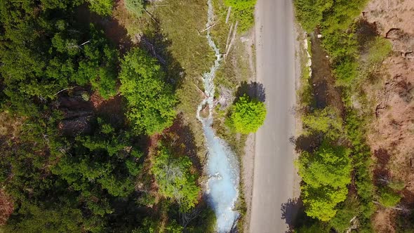 Aerial view moving towards hot spring flowing next to road alt
